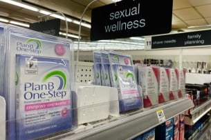 Boxes of Plan B sit on a shelf in a pharmacy under a sign that reads "sexual wellness"