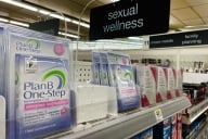 Boxes of Plan B sit on a shelf in a pharmacy under a sign that reads "sexual wellness"