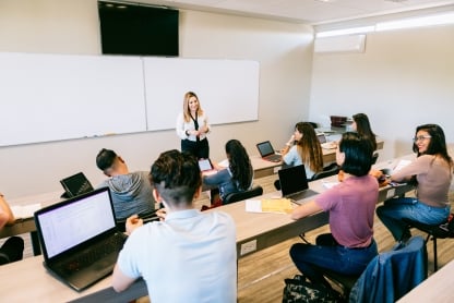 Teacher warmly engaging with diverse university students in a classroom