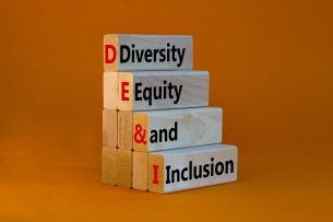 A stack of four blocks, each bearing one of the words "Diversity," Equity" "and" "Inclusion," against an orange background.