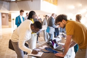 A staged image of someone signing a form while checking into a conference.