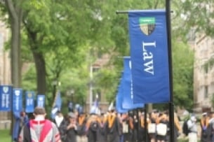 Blue flags with the word "Law" printed on them are attached to lightposts on Yale Law School's campus.