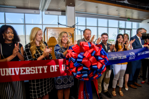 Leaders from the University of Utah and Salt Lake Community College unite a red ribbon with a blue ribbon, joining at a red and blue bow.