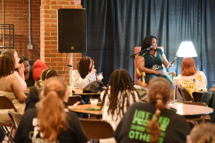 Students face President Mary Dana Hinton on stage in the Hollins University Rathskellar.